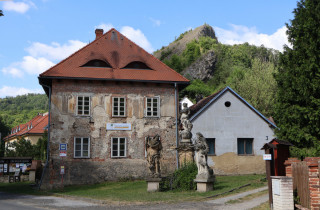 Hned u zastávky autobusu najdeme informační centrum a před ním pískovcové mariánské sousoší. z roku 1731, pravděpodobně z dílny Františka Ignáce Weisse. Na nejvyšším podstavci stojí Panna Marie s žezlem v ruce a pod ní sv. Jan Křtitel s beránkem a sv. Ivan s laní.