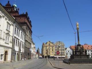 Vyústění Pražské ulice na náměstí Republiky v Plzni, vlevo radnice, vpravo morový sloup a uprostřed rohový dům se žlutou fasádou, za nímž se nachází dům U Salzmannů.
