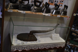 Ve vitríně je mohutná žehlička dovezená z Egypta.
